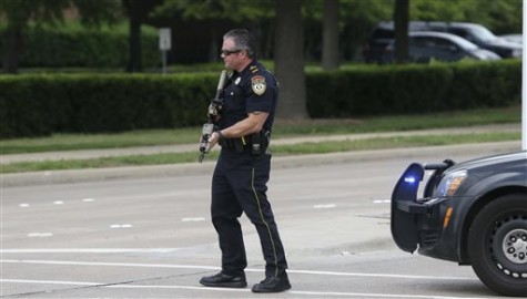A Garland Police Officer stands guard at the road leading to Naaman Forest High School and Curtis Culwell Center after a fire alarm was called at the high school, Tuesday, May 5, 2015, in Garland, Texas. A man whose social media presence was being scrutinized by federal authorities was one of two suspects in the Sunday shooting at this location that hosted a cartoon contest featuring images of the Muslim Prophet Muhammad. The Islamic State group on Tuesday claimed responsibility for the attack. (AP Photo/LM Otero)