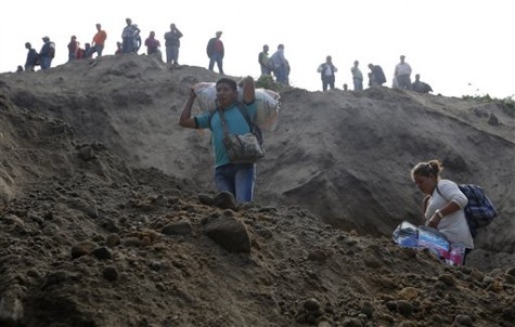 Evacuating residents watch rescue efforts after a landslide hit Santa Catarina Pinula, on the outskirts of Guatemala City, Friday, Oct. 2, 2015. Recent rainfall provoked the landslide, affecting dozens of homes. (AP Photo/Moises Castillo)