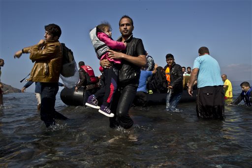 A Syrian refugee man carrying his daughter rushes to the beach as he arrives on a dinghy from the Turkish coast to the northeastern Greek island of Lesbos, Sunday, Oct. 4 , 2015. The U.N. refugee agency is reporting a noticeable drop this week in arrivals of refugees by sea into Greece - as the total figure for the year nears the 400,000 mark. Overall, the UNHCR estimates 396,500 people have entered Greece via the Mediterranean this year with seventy percent of them are from war-torn Syria. (AP Photo/Muhammed Muheisen)