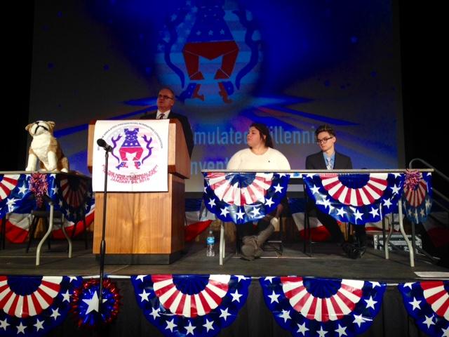 Mr. Brian Haley, with convention chairs Katie Solomon and JT Monserrat, speaks at the podium at the start of the 2016 Simulated Presidential Convention.