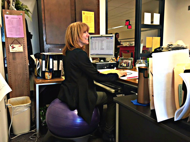 Perfect Posture: NPHS attendance secretary Karen Henkels conducts her morning work on her new chair. The exercise ball chairs are an effort by those in Home Office K31 to improve their physical health while also conducting their work in what is normally a more sedentary environment. 