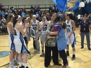 Surrounded by her team, girls' basketball coach Maggie deMarteleire embraces team manager Rachel Grace following the coach's 500th career win.