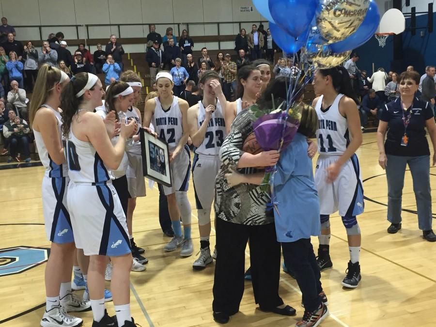 Surrounded by her team, girls basketball coach Maggie deMarteleire embraces team manager Rachel Grace following the coachs 500th career win.