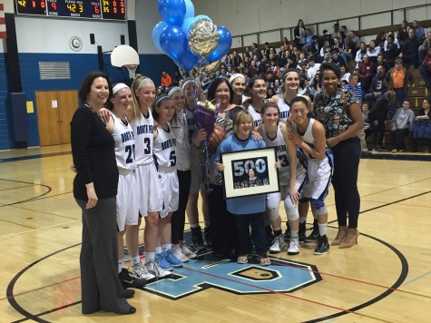 The girl's basketball team crowds around deMarteleire following the game to celebrate their coaches milestone win.