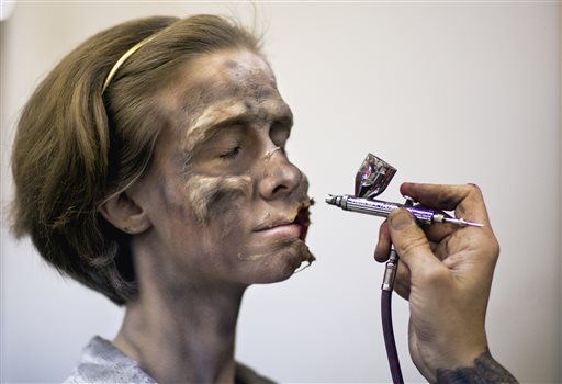 Lacy Dearring, of Lawrenceville, Ga., left, is worked on by makeup artist Lucas Godfrey to look like a zombie at Walker Stalker Con, a convention based off the cable TV show The Walking Dead, Sunday, Nov. 3, 2013, in Atlanta. The convention, which ran through the weekend, was expected to draw about 10,000 participants says co-creator Eric Nordhoff. The Walking Dead characters battle zombies known as walkers in the streets of downtown Atlanta and in forests, small towns and a prison south of the city. The convention featured appearances by some of the shows actors as well as games, toys, comic and other memorabilia for-fans of zombie, horror and science fiction. (AP Photo/David Goldman)