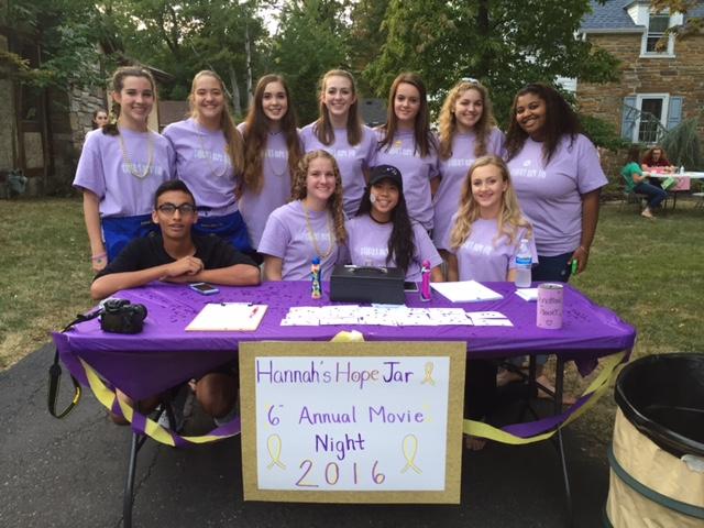 Hannah Garder, pictured in the center of the back row, poses for a photo with her volunteers at the check in station from her 6th annual movie night to benefit childhood cancer.