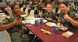 (Left to right) Cadet Senior Master Sergeant Bell, Cadet Airman Basic Darragh, and Scholl eating breakfast before a C-150J Hercules flight at encampment.
