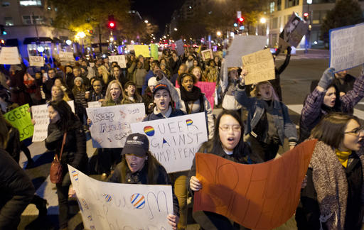 Protesters hold banners as they protest during a march in downtown Washington in opposition of President-elect, Donald Trump, Saturday, Nov. 12, 2016. Tens of thousands of people marched in streets across the United States on Saturday, staging the fourth day of protests of Donald Trumps surprise victory as president. (AP Photo/Jose Luis Magana)