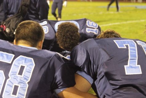 Jason Prince 16, Zach Lavalla 58, and Keith Caputo 71take a moment to pray at a football game.