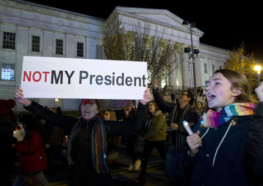 A demonstrator holds a banner as they protest during a march in downtown Washington in opposition of President-elect Donald Trump, on Saturday, Nov. 12, 2016. More than 200 people, carrying signs, gathered on the steps of the Washington state Capitol. The group chanted not my president and no Trump, no KKK, no fascist USA. ( AP Photo/Jose Luis Magana)