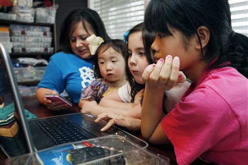 In this April 4, 2013 photograph, the Smith women, from left, mother Niki Smith, GiGi, 3, Macy Jade, 7 and Guan Ya, 14, use Google Translate on the family laptop to speak with their new daughter, Guan Ya, in their Rienzi, Miss., home. The Smiths and their children are using the Google Translate program to communicate almost exclusively with Guan Ya, who is deaf. The family uses iPhones, iPods and a laptop, all loaded with the program to write in either English that translates to Chinese or vice-a-versa. (AP Photo/Rogelio V. Solis)