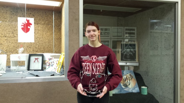 Cara Elam poses with her sculpture, Baby Face