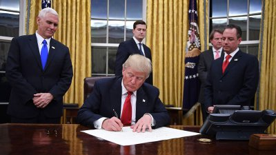 President Donald Trump signs an executive order as Vice President Mike Pence and Chief of Staff Reince Priebus look on at the White House in Washington, DC on January 20, 2017. (Photo: JIM WATSON/AFP/Getty Images)