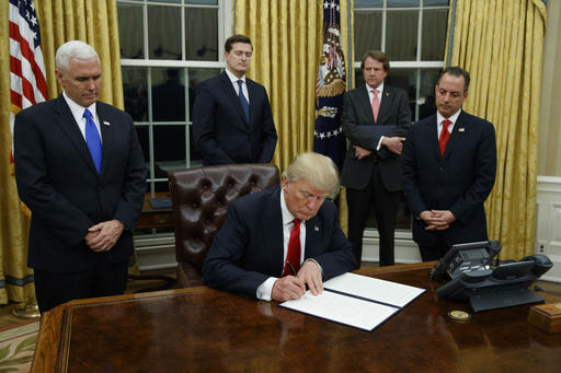 FILE - In this Jan. 20, 2017, file photo,President Donald Trump, flanked by Vice President Mike Pence and Chief of Staff Reince Priebus, signs his first executive order on health care in the Oval Office of the White House in Washington. After years of objecting to President Barack Obamas use of executive power to work around Congress, President Donald Trump and Republicans allies have all-but abandoned their public complaints about checks-and-balances and embraced the go-it-alone strategy to fast-track their dismantling President Barack Obamas policies. (AP Photo/Evan Vucci, File)