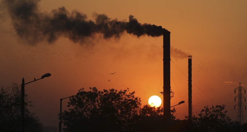 FILE - This is a Monday, Dec. 8, 2014 file photo of birds as they fly past at sun set as smoke emits from a chimney at a factory in Ahmadabad, India. The U.N.s scientific panel on climate change will write a special report on how to limit global warming to 1.5 degrees Celsius (2.7 degrees Fahrenheit) compared with pre-industrial times. Temperatures have already risen almost 1 degree C (1.8 F) since humans started burning fossil fuels  the biggest source of greenhouse gases  on an industrial scale in the 19th century. (AP Photo/Ajit Solanki, File)