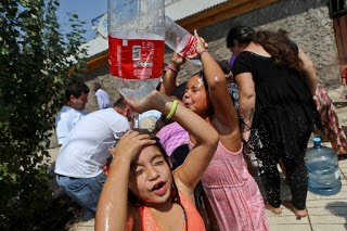 Caption for image: Two girls cool off while residents gather water from a fire hydrant in a neighborhood in Santiago, Chile on Monday, February 27, 2017. Millions are without drinkable water in Santiago’s greater Metropolitan area after floods and mudslides limit supplies. (AP Photo/Esteban Felix)