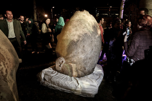 People gather around part of a statue, the head of King Psamtek 1, after a press conference at the Egyptian museum in Cairo, Thursday, March 16, 2017. The three-ton torso of the massive statue King Psamtek 1 was lifted on Monday from mud and groundwater where it was recently discovered in a Cairo slum. (AP Photo/Nariman El-Mofty)