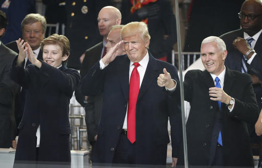 President Donald Trump, center, salute with his son Barron, left, and Vice President Mike Pence as they view the 58th Presidential Inauguration parade for President Donald Trump in Washington. Friday, Jan. 20, 2017 (AP Photo/Pablo Martinez Monsivais)