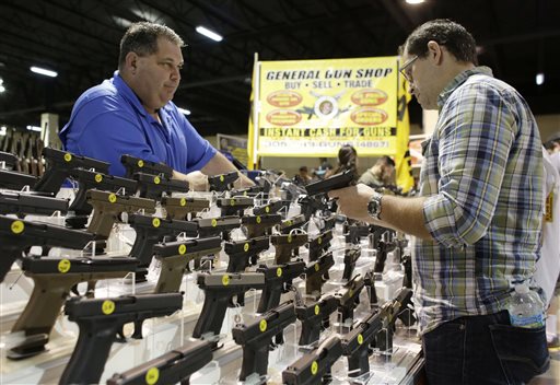 Julio Piloto, owner of General Gun Shop, left, shows customer Pedro Silva, of Homestead, Fla., right, a Glock 19 at a gun show held by Florida Gun Shows, Saturday, Jan. 9, 2016, in Miami. President Barack Obama announced proposals this week to tighten firearms sales through executive action. (AP Photo/Lynne Sladky)