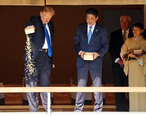 President Donald Trump feeds Koi fish as Japan Prime Minister Shinzo Abe, center, and Secretary of State Rex Tillerson second from right, watch during a stop at a Koi pond during a visit to the Akasaka Palace, Monday, Nov. 6, 2017, in Tokyo. Trump is on a five country trip through Asia traveling to Japan, South Korea, China, Vietnam and the Philippines. (AP Photo/Andrew Harnik)