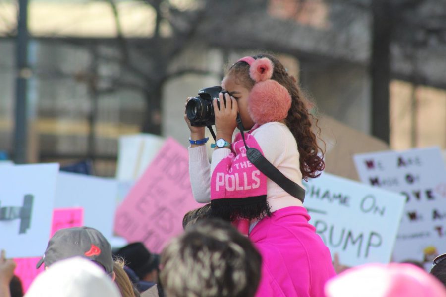 A young marcher gets a higher view while taking some photos of the demonstration.