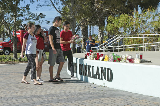 Students place flowers on the stage outside the Pines Trail Center where a candlelight vigil will be held, Thursday, Feb. 15, 2018, in Parkland, Fla. Nikolas Cruz is accused of opening fire Wednesday at Marjory Stoneman Douglas High School in Parkland, Fla., killing more than a dozen people and injuring several. (AP Photo/Joel Auerbach)
