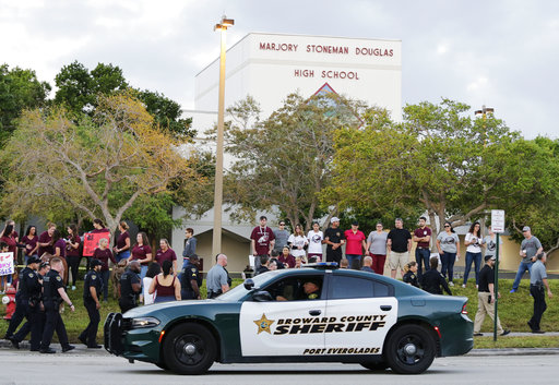 In this Feb. 28, 2018 photo, a police car drives by Marjory Stoneman Douglas High School in Parkland, Fla., as students returned to class for the first time since a former student opened fire there with an assault weapon. The United States is in the midst of a national debate over school security after the mass shooting at a Florida school. To President Donald Trump and gun supporters, the solution is to put more guns in the hands of trained school staff _ including teachers _ to play defense against a rampaging gunman. The rest of the world has different strategies to deal with violence around schools. But the U.S. appears to be the only place in the world that wants to arm teachers to the degree the president wants.   (AP Photo/Terry Renna)