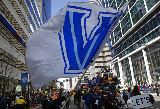 A student waves a Villanova flag in front of buses carrying members of the Villanova basketball team during a parade celebrating their NCAA college basketball championship, Thursday, April 5, 2018, in Philadelphia. Villanova defeated Michigan on Monday for the NCAA mens basketball title. (AP Photo/Patrick Semansky)