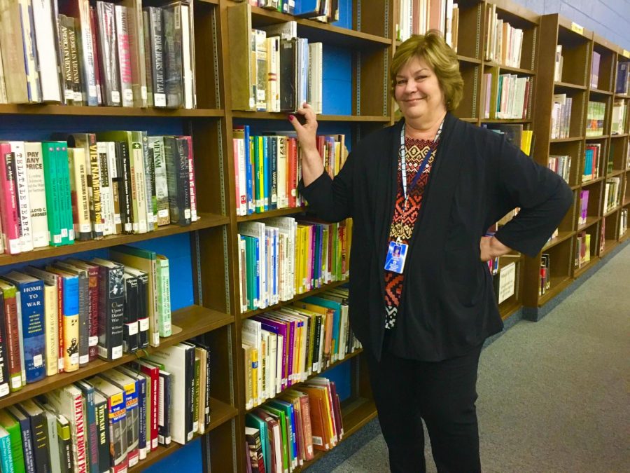 Library secretary Janice Johnson poses by the bookshelves. Johnson will retire this year.
