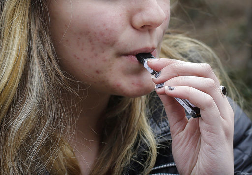FILE - In this April 11, 2018, file photo, an unidentified 15-year-old high school student uses a vaping device near the schools campus in Cambridge, Mass. A school-based survey shows nearly 1 in 11 U.S. students have used marijuana in electronic cigarettes, heightening concern about the new popularity of vaping among teens. E-cigarettes typically contain nicotine, but results published Monday, Sept. 17, mean a little more than 2 million middle and high school students have used the devices to get high. (AP Photo/Steven Senne, File)