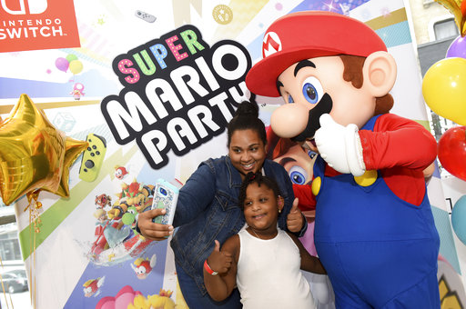 IMAGE DISTRIBUTED FOR NINTENDO OF AMERICA - Shirley M. and Gabriella A., 5, of New York, NY, celebrate the launch of the Super Mario Party and Luigis Mansion games by posing with Mario during a special event at the Nintendo NY store in Rockefeller Plaza on Sunday, Oct. 7, 2018, in New York. An action-packed party game with 80 interactive mini-games, Super Mario Party is now available for the Nintendo Switch system. (Diane Bondareff/AP Images for Nintendo of America)