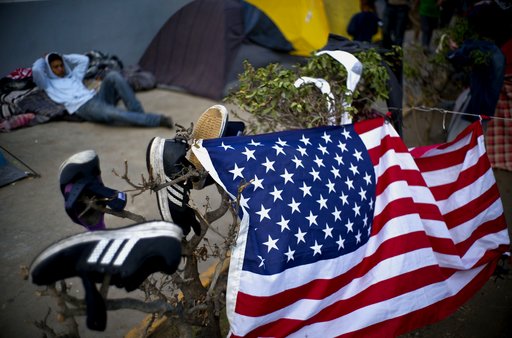 A migrant, part of the migrant caravan, rest next to U.S. flag and shoes drying in the sun, at a sports complex where more than 5,000 Central American migrants are sheltering in Tijuana, Mexico, Wednesday, Nov. 28, 2018. As Mexico wrestles with what to do with the thousands of people camped out in the border city of Tijuana, President-elect Andres Manuel Lopez Obradors government signaled that it would be willing to house the migrants on Mexican soil while they apply for asylum in the United States, a key demand of U.S. President Donald Trump. (AP Photo/Ramon Espinosa)