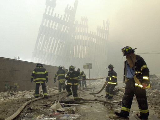 FILE - In this Sept. 11, 2001 file photo, with the skeleton of the World Trade Center twin towers in the background, New York City firefighters work amid debris on Cortlandt St. after the terrorist attacks. On Friday, Feb. 15, 2019, Rupa Bhattacharyya, the September 11th Victim Compensation Fund special master, announced that the compensation fund for victims of the Sept. 11, 2001 terror attacks will cut future payments by 50 to 70 percent because the fund is running out of money. (AP Photo/Mark Lennihan, File)