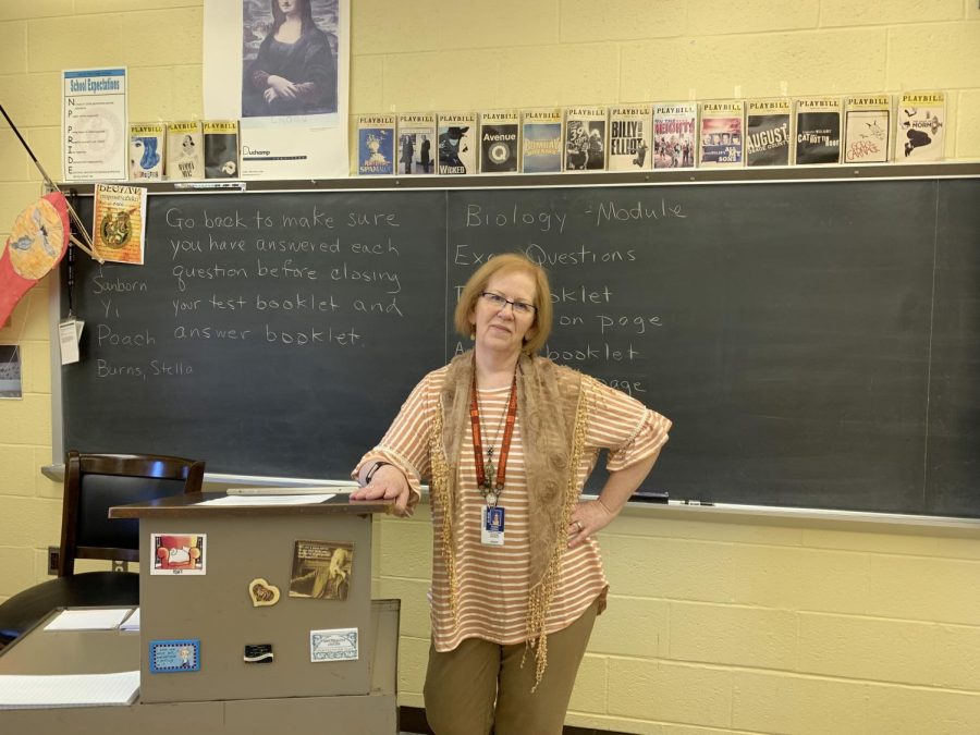 Mrs. Sue Cassel poses in front of her playbills and chalkboard.