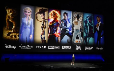 FILE - In this April 3, 2019, file photo characters from Disney and Fox movies are displayed behind Cathleen Taff, president of distribution, franchise management, business and audience insight for Walt Disney Studios during the Walt Disney Studios Motion Pictures presentation at CinemaCon 2019, the official convention of the National Association of Theatre Owners (NATO) at Caesars Palace in Las Vegas. On Tuesday, Nov. 12, Disney Plus launches its streaming service. (Photo by Chris Pizzello/Invision/AP, File)