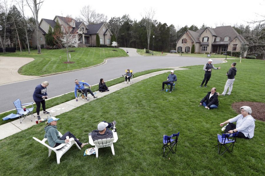 Neighbors have an informal gathering while keeping a safe distance because of the corona virus Sunday, March 22, 2020, in Nolensville, Tenn. (AP Photo/Mark Humphrey)