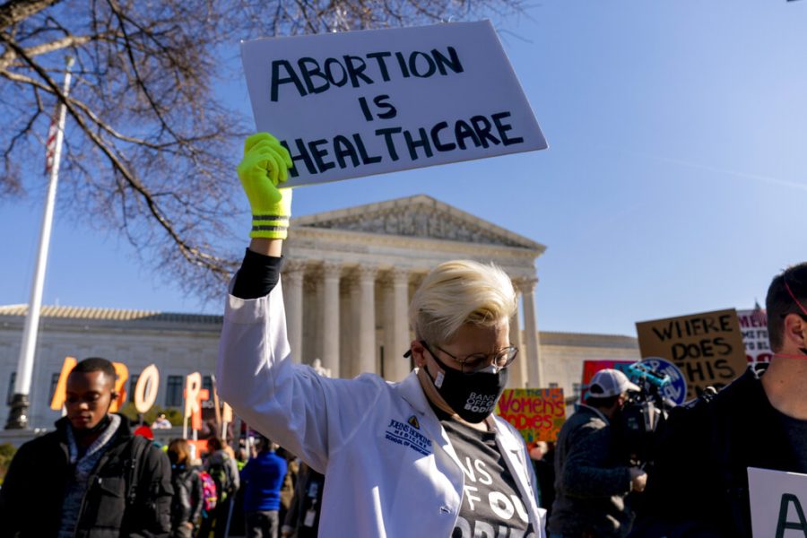A+woman+in+an+doctors+uniform+holds+a+poster+that+reads+Abortion+is+Healthcare+as+abortion+rights+advocates+and+anti-abortion+protesters+demonstrate+in+front+of+the+U.S.+Supreme+Court%2C+Wednesday%2C+Dec.+1%2C+2021%2C+in+Washington%2C+as+the+court+hears+arguments+in+a+case+from+Mississippi%2C+where+a+2018+law+would+ban+abortions+after+15+weeks+of+pregnancy%2C+well+before+viability.+%28AP+Photo%2FAndrew+Harnik%29