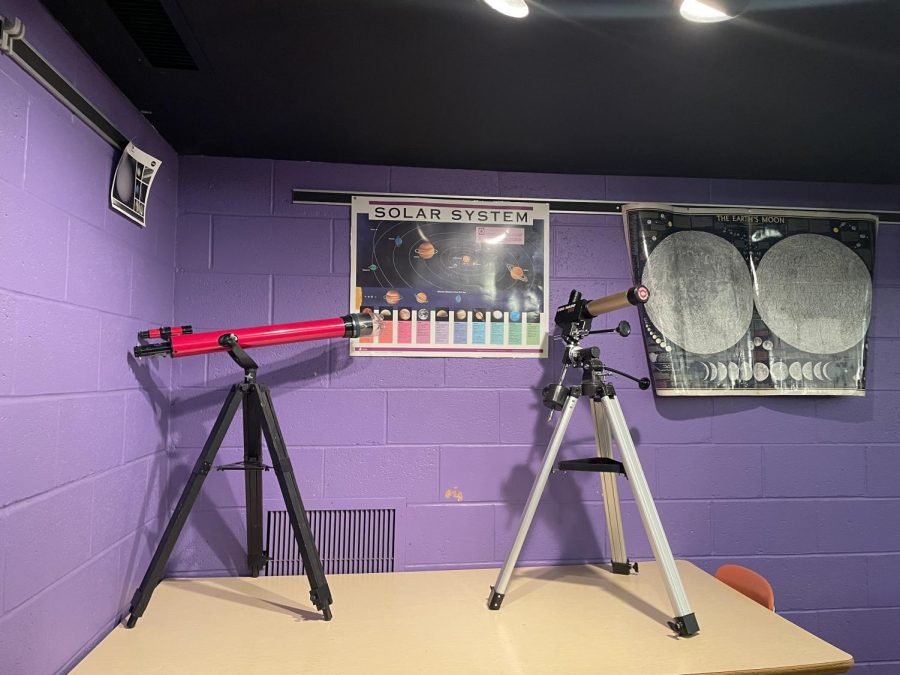 Telescopes and posters adorn the purple brick walls. 