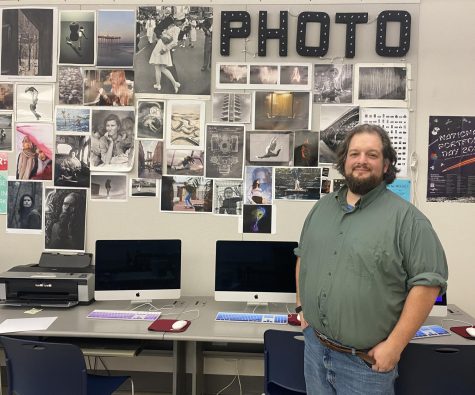 Raab poses in front of his photography students work.