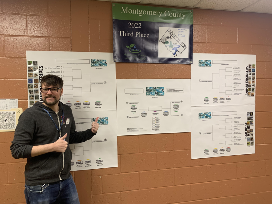 Mr. Collier poses with his giant March Mammal Madness bracket outside his room.